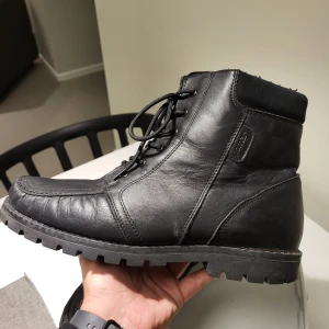 Svarta Pomar Finland boots med snörning och dragkedja stl 44 - Säljer ett par svarta Pomar boots i skinn med grov sula, snörning framtill och dragkedja på sidan. Insidan är fodrad med mjukt material och skaften har mockadetaljer upptill. Perfekt för dig som gillar robust stil och vill ha något som funkar hela hösten och vintern.