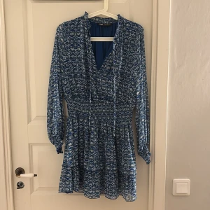 Blå mönstrad kortklänning från Zara - Supersnygg blå kortklänning från Zara med vitt mönster och v-ringad hals. Köpt på plick. Storlek M men passar mig som bär xs/s☺️☺️