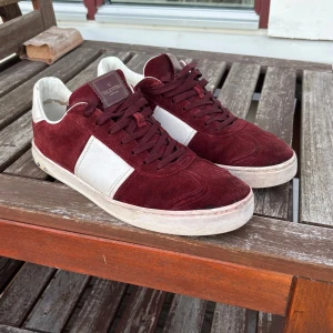 Valentino flycrew vinröda sneakers - Snygga Valentino Rockrunner sneakers i vinröd mocka och vitt skinn. Skorna har klassisk snörning, platt sula och coola nitar baktill. Perfekt för dig som vill sticka ut med exklusiva detaljer och en djup färgton. Cond 7/10 2 nitar borta och lite slitna inuti . Men inget som märks vid användning! Inge og