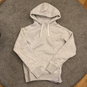 (Ny) Ljusgrå hoodie från Russemerch - Säljer en stilren ljusgrå hoodie från Russemerch i storlek medium. Tröjan har huva med snörning, magficka och mjukt material som känns skönt mot huden. Perfekt för chill dagar eller när du vill ha en enkel och snygg look. Helt oanvänd med lappen kvar och allt. Fraktas i original förpackning. Nypris 500 (650 med frakt) mitt pris 400!