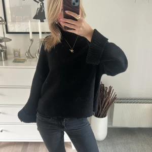 Svart polotröja från Vero Moda XS - Mysig svart polotröja från Vero Moda i storlek XS. Tröjan har en hög krage, långa ärmar med breda muddar och är stickad i ett mjukt material. Perfekt för kyliga dagar och enkel att styla med jeans eller kjol.