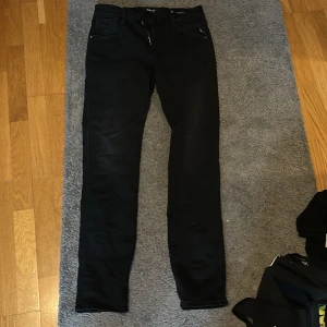 Replay Anbass Hyperflex svarta jeans - Svarta Replay Anbass Hyperflex jeans i slim fit med klassisk femficksdesign. Jeansen är tillverkade i stretchigt material som ger extra rörelsefrihet och komfort. Snygg, stilren look med diskreta detaljer och dragkedja i gylfen. Helt nya! Använda 1 gång hemma, och dem är tvättade 1 gång.