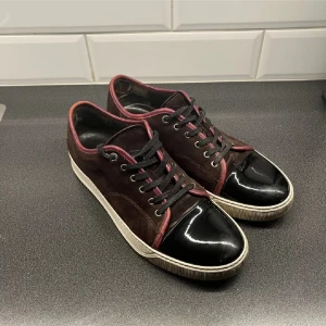 Lanvin sneakers i mocka och lack - Säljer mina vinröda lanvins som är väldigt sällsynt. Skicket är super där den har vanlig används defekter samt en defekt i hälen som är lätt att fixa hos en skomakare om man är i behov, skulle säga att skicket är 8/10. Skorna är i strl UK 8 vilket är 42 tror jag men passar 43 och 44 också. Priset är 1699 vilket är SJUKT bra. öppen för byten och skriv vid minsta funderingen!😇