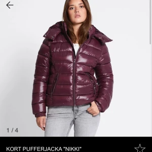 Lager 157 jacka  - Säljer en kort, glansig vinröd pufferjacka från Nikki med huva och dragkedja framtill. Den är endast använd en gång så alltså i nyskick, slutsåld hemsidan