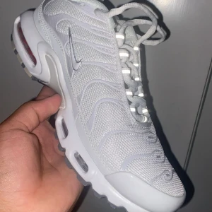Nike Air Max Plus vita sneakers - Nike Air Max Plus sneakers i helvitt med mesh- och syntetöverdel, ikoniska vågformade detaljer och synliga Air Max-enheter i sulan. Skorna har snörning och en chunky, sportig vibe som sticker ut. Perfekta för dig som gillar en clean och modern look.
