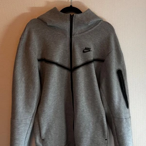 Nike tech i grå - En grå snygg zip hoodie i storlek S. Nästan aldrig använd, helt perfekt skick. Hör av er vid frågor! 