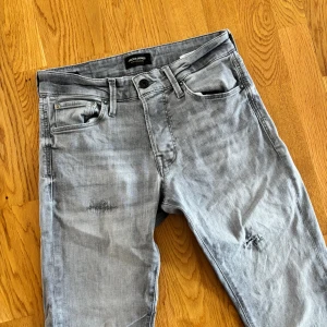 Jack&jones jeans - Säljer gråa jeans med slitningar från jack & Jones. Storlek 29/32. Bra skick men lite vit bredvid slitningen på höger sida som man ser på bild ett. Bara o skriva vid frågor eller funderingar.