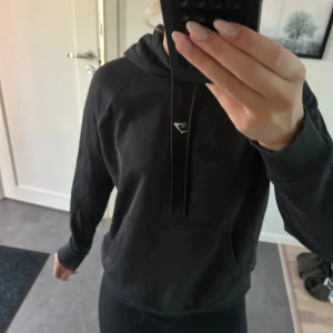 Svart hoodie - Svart hoodie från Gymshark i storlek M. Klassisk modell med huva, snörning och magficka. Bra skick och skulle säga att den sitter som S.
