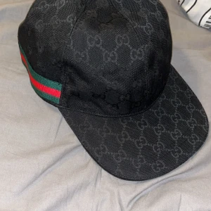 Svart Gucci keps - Säljer en svart Gucci keps, använd bara på sommaren. Den är som ny. Inga skador eller defekter. Storlek L men är justerbart. Passar alla. Dm för fler bilder eller funderingar.