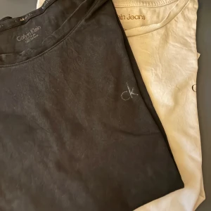 2-pack Calvin Klein t-shirts, svart & vit - Två stilrena t-shirts från Calvin Klein Jeans i svart och vit. Båda har klassisk rund hals, kort ärm och diskret 'ck'-brodyr på bröstet. Regular fit och tillverkade i mjuk bomull – perfekta till jeans eller shorts. Vill du köpa en så får du det för 60kr o båda för 100kr