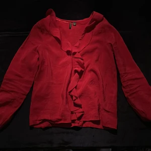 Röd blus med volanger från Vero Moda - Fin röd blus från Vero Moda. Den är i storlek S. Säljer på grund av att den inte kommer till användning och den är aldrig använd.😊❣️