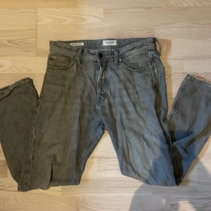 Grå jeans från Jack & Jones relaxed fit - Säljer ett par grå jeans från Jack & Jones i relaxed fit-modell. Byxorna har klassisk femficksdesign, raka ben och normal midja. Materialet är robust denim i bomull och färgen är snyggt tvättad grå. Perfekta för en chill och avslappnad stil.