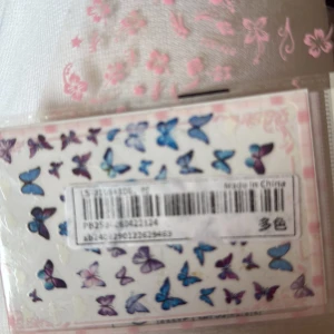 Blå och lila fjäril nagelstickers - Söta nagelstickers med fjärilar i blått och lila, perfekta för att dekorera naglarna och skapa en unik look. Flera olika storlekar och former på fjärilarna. Kommer på ett ark och är enkla att applicera.