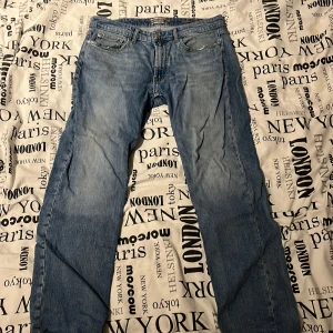 Blå regular fit jeans från Dressmann - Säljer ett par klassiska blå jeans från Dressmann i regular fit. Jeansen har fem fickor, dragkedja och knapp framtill samt raka ben. Perfekta för dig som gillar en tidlös och enkel stil. Materialet är slitstarkt jeans i bomull.