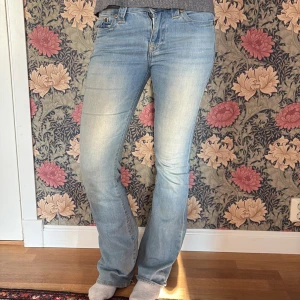 True Religion Becca Bootcut Jeans ljusblå - Ljusblå jeans från True Religion, modell Becca Mid Rise Bootcut. Snyggt slitna detaljer och klassiska bakfickor med dekorativa nitar. Jeansen har medelhög midja och bootcut-ben, tillverkade i mjuk denim med stretch.