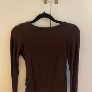 Brun långärmad topp från Veromoda  - Säljer en brun långärmad topp från Veromoda i storlek XS. Toppen har en enkel, rund halsringning fram och en djup öppen rygg som ger en snygg och modern look. Den är i storlek XS men passar även S