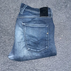 Replay Anbass hyperflex jeans  - Säljer ett par Replay Anbass jeans i mörkblå tvätt med slitningar och slim fit. Klassisk femficksmodell med snygga detaljer och kontrastsömmar. Tyvärr har de gått upp och har hål i grenenen vilket kanske går att åtgärda om man är heller känner någon som är kunnig. W34, L storleken är tyvärr okänd men jag bedömer den till L32 (jag på bilden är 181cm) 1