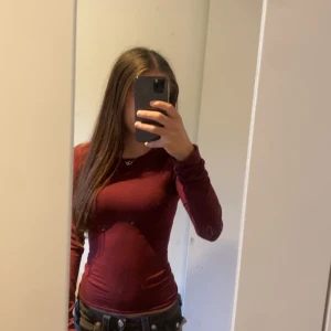 Vinröd långärmad topp - Säljer en vinröd långärmad topp med tight passform. Enkel och stilren design som sitter snyggt på kroppen. Perfekt att matcha med jeans eller kjol för en trendig look.