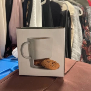 Cookie Mug - Smart och praktisk mugg med ett fack för kakor, perfekt för kaffe eller te och snacks. Muggen är diskmaskinssäker och levereras i originalförpackning. Produkten ser helt ny ut utan synligt slitage eller defekter. Perfekt present till fikastunden!