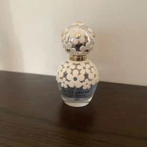 Daisy Dream parfym från Marc Jacobs - Daisy Dream från Marc Jacobs har en lekfull design och innehåller noter av björnbär, päron, grapefrukt, blåregn, litchi, jasmin, mysk, vitt trä och kokosvatten. Perfekt för dig som gillar fruktiga och fräscha dofter. 50ml flaska med ca halva kvar. 