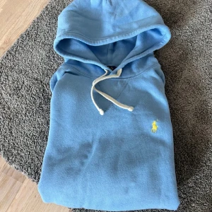Blå Ralph Lauren Hoodie - Säljer en väldigt unik ljusblå Ralph Lauren hoodie i nyskick. Inga defekter på Hoodien. Storlek L. Äkta som man kan se på sista bilden. Pris kan diskuteras vid snabb affär!