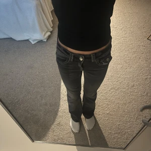 Svarta bootcut jeans låg midja - Säljer ett par svarta jeans med låg midja. Modellen har bootcut-ben och klassiska fickor både fram och bak. Jeansen har en cool, lite tvättad look och passar perfekt till en trendig vardagsstil. Säljer dem för att dem blivit för korta.
