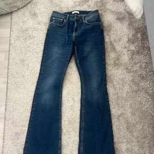 Blå bootcut jeans från Perfect Jeans - Snygga blå jeans från Perfect Jeans i klassisk bootcut-modell. Jeansen har fem fickor, orangea sömmar och en mörk tvätt med lätt slitning. Tillverkade i jeansmaterial med normal passform och medelhög midja. Perfekta för dig som gillar en tidlös look.