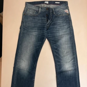 Blå Replay Billstrong jeans straight fit - Säljer ett par blå Replay Billstrong jeans med klassisk femficksdesign och snygga slitningar. Jeansen har raka ben, normal passform och tydliga Replay-detaljer som logga på fickan och bak på linningen. Tillverkade i slitstarkt jeanstyg med kontrastsömmar.