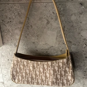 Beige axelväska med monogrammönster - Köpt begagnad, använt den en gång. Lite smutsig på insidan men går lätt att ta bort. Handtaget är lite avskavt på baksidan men inget man ser. Ej äkta 🫶🏻