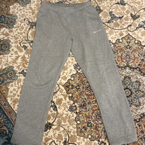 Grå mjukisbyxor från Champion M - Grå mjukisbyxor från Champion i storlek medium. Byxorna har elastisk midja och är tillverkade i mjukt material med borstad insida för extra komfort. Diskret Champion-logga på ena benet. Perfekta för chill eller träning.