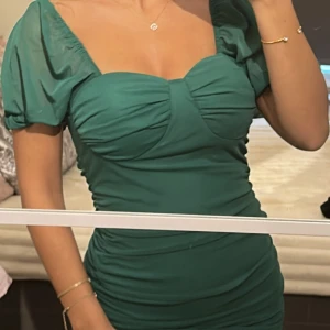 Grön kortklänning från Misscix - Supersnygg grön kortklänning från Missicx med puffiga kortärmar och rynkade detaljer längs sidorna. Klänningen har en söt sweetheart-ringning och är tillverkad i ett mjukt, lätt polyestertyg som ger en skön passform. Perfekt för dig som vill sticka ut med färg och stil. Storlek S. 