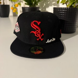 Svart New Er 59FIFTY White Sox keps - Snygg svart 59FIFTY keps från New Er med Chicago White Sox logga i rött framtill och broderad All Star Game 2003 patch på sidan. Just Don brodyr på framsidan och MLB-logga bak. Tillverkad i 100% polyester, klassisk flat brim och fitted passform.
