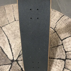 Santa Cruz Skateboard - Santa Cruz skateboard i färgstark design med robusta hjul och truckar. Brädan är i mycket gott skick, med fräsch griptape och inga synliga skador eller slitage. Perfekt för både nybörjare och erfarna åkare som söker kvalitet och stil.