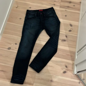Mörkblå  jeans Jack & Jones 31/30 - Snygga mörkblå jeans från Jack & Jones i storlek 31/30. Jeansen har klassisk femficksdesign, svarta sömmar och en diskret tvättad look. Perfekta för dig som gillar en tight passform och stilren vibe.