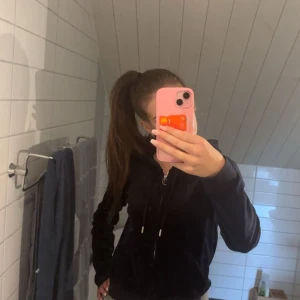 Juicy Couture marinblå velour hoodie - Juicy Couture hoodie i mjuk marinblå velour med dragkedja och snörning i huvan. Klassisk logga broderad på bröstet och snygga detaljer i silver. Perfekt för en chill och trendig look. Mycket bra skick då den knappt använts! Storlek S