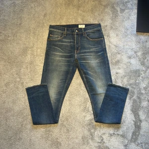 Tiger of Sweden blå jeans straight fit - Blå jeans med snygg tvätt från Tiger of Sweden med klassisk femficksdesign och orangea kontrastsömmar. Jeansen har en rak passform och är tillverkade i slitstarkt denim. Perfekta för dig som gillar en tidlös och stilren look.