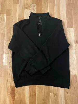 Svart Quarter Zip Fleece Lager 157 - Mysig svart fleece med half zip från 157. Tröjan har hög krage, långa ärmar och ribbade muddar. Perfekt för kyliga dagar och enkel att matcha med det mesta. Insidan är mjuk och värmande.