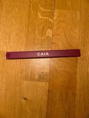 CAIA läppenna Ruby Plum - Säljer en CAIA läppenna i färgen Ruby Plum. Pennan har en snygg vinröd/plommonröd nyans och kommer i en stilren, avlång förpackning med CAIA-loggan. Perfekt för att definiera och fylla i läpparna med en krämig och pigmenterad formula.