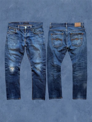 *SELVAGE* GRIM TIM - Ett par Nudie selvage jeans med en galen tvätt och en schysst slitning på knät som jag verkligen diggar! Slim fit. Det står W31 inuti men gå alltid efter måtten. Pyttelite slitet i översta knapphålet - inget trasigt! Hör av dig vid frågor! Mått: Ytterbenslängd - 95 cm, Midja - 41 cm, Bensöppning - 18 cm