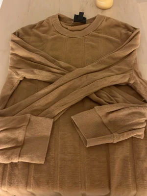 Beige stickad tröja från H&M - Säljer en beige stickad tröja från H&M i slim fit-modell. Tröjan har rund halsringning, långa ärmar och diskreta vertikala ränder i strukturen. Perfekt för dig som gillar en enkel men stilren look.