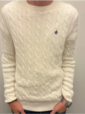 Vit kabelstickad tröja från Morris - Säljer en vit kabelstickad tröja från Morris med rund hals och diskret logga broderad på bröstet. Tröjan har långärmade ribbade muddar och är gjord i mjukt stickat material som passar perfekt till kyliga dagar. Den är i storlek S men skulle vilja säga att den sitter mer som M