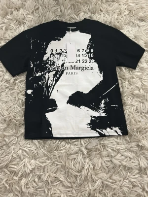 Maison Margiela svart/vit t-shirt - Maison Margiela t-shirt i svart och vitt. Skickas i och med förp. ( se bild 4 ). Alla lappar sitter kvar, använd 1 gång innan.