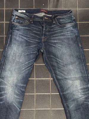 Jack & Jones "Comfort" Jeans – W32 L34 (Toppskick!) - Kan gå ner i pris ordentligt vid snabb affär! Säljer ett par riktigt schyssta jeans från Jack & Jones i modellen "Comfort". De har en klassisk blå tvätt med snygga, diskreta slitningar och kontrastsömmar som ger en tidlös look. Jeansen har raka ben, fem fickor och den klassiska läderpatchen bak.  Skick: Mycket bra, nästan som nya! De har bara blivit liggande i garderoben och säljes nu på grund av att de tyvärr inte kommer till användning längre. 