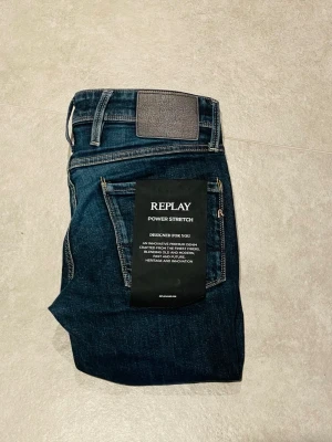Replay Anbass slim jeans - Säljer ett par mörkblå Replay Anbass jeans med slim fit och power stretch. Klassisk femficksmodell med snygga kontrastsömmar och läderpatch bak i midjan. Jeansen är tillverkade i stretchig denim för extra komfort och har en modern, smal passform.
