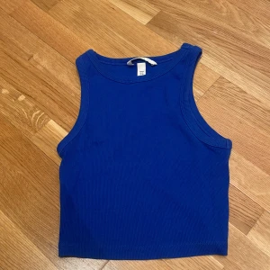 Blå ribbad linnetopp från H&M - Säljer en blå croppad linnetopp från H&M i storlek XS. Toppen är ribbad och ärmlös med rund halsringning. Perfekt till sommaren och enkel att matcha med jeans eller kjol.