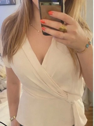 Krämvit blus med knyt - Säljer en krämvit blus med knyt i sidan och v-ringad hals. 