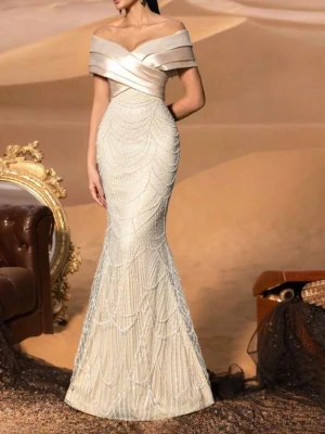 Champagnefärgad långklänning S - Säljer en elegant champagnefärgad långklänning med offshoulder-ringning och glittriga paljettdetaljer. Klänningen har figurnära passform, vackra draperingar upptill och ett skimrande mönster över hela kjolen. Perfekt för bal eller nyår!