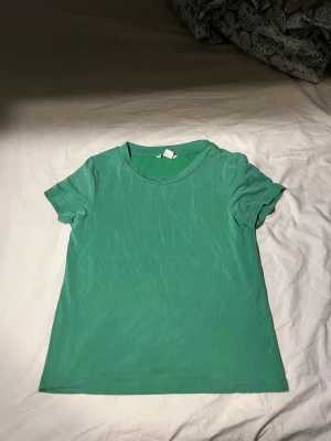 Grön t-shirt från Monki  - Säljer en enkel grön t-shirt från Monki i storlek XS. T-shirten har rund hals och korta ärmar, tillverkad i mjuk bomull. Perfekt för dig som gillar basic och vill ha en chill tröja. Väldigt mjukt och skönt tyg!