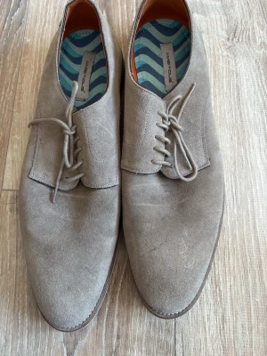 Beige mockaskor från Ambitious - Snygga beige mockaskor från Ambitious med klassisk snörning och rund tå. Skorna har en stilren design och är tillverkade i mjuk mocka som ger en exklusiv känsla. Perfekta för dig som vill ha en clean och modern look.