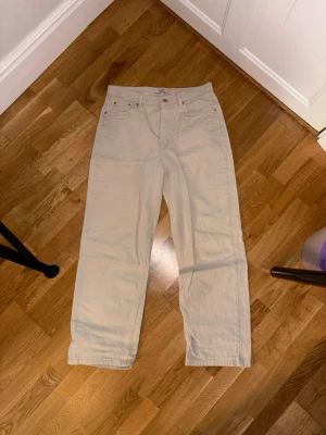 Beiga raka byxor från NA-KD, strl 40 - Säljer ett par beiga byxor från NA-KD i rak modell. De har klassisk femficksdesign, knapp och dragkedja framtill. Materialet är kraftig bomull